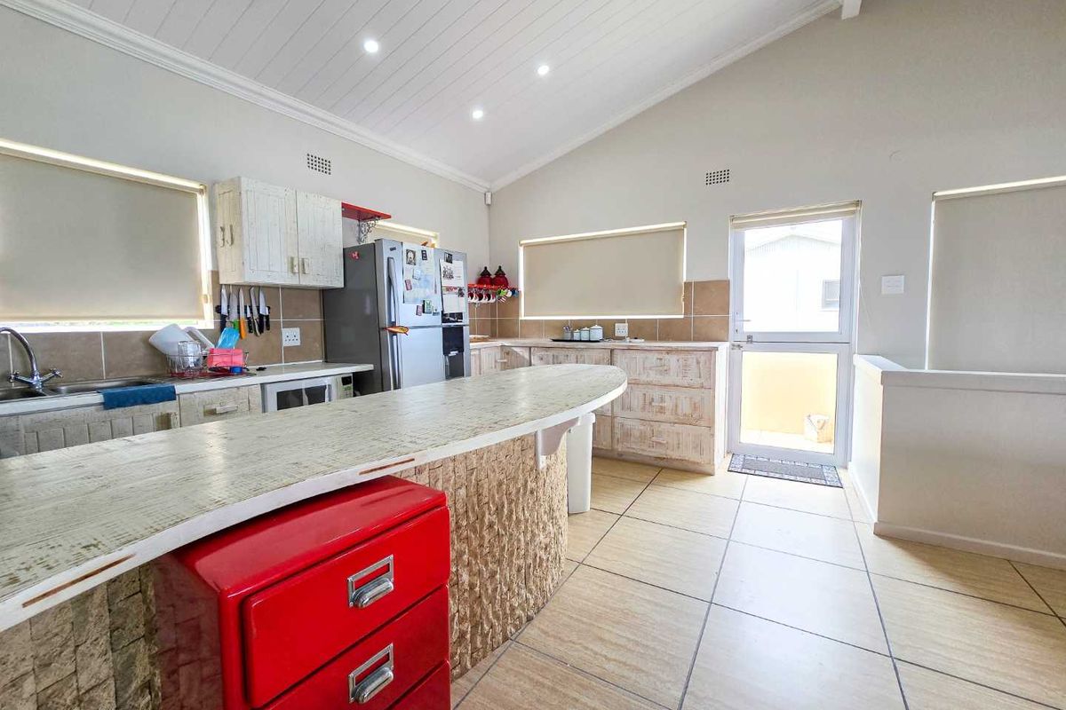Spacious kitchen featuring a breakfast bar, tiled flooring, vaulted ceilings with recessed lighting, and direct access to an outdoor area.