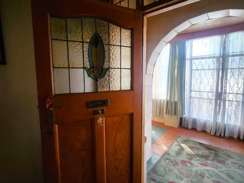 Entrance area featuring a character timber door with leaded glass detailing, an arched transition, and terracotta floor tiles.