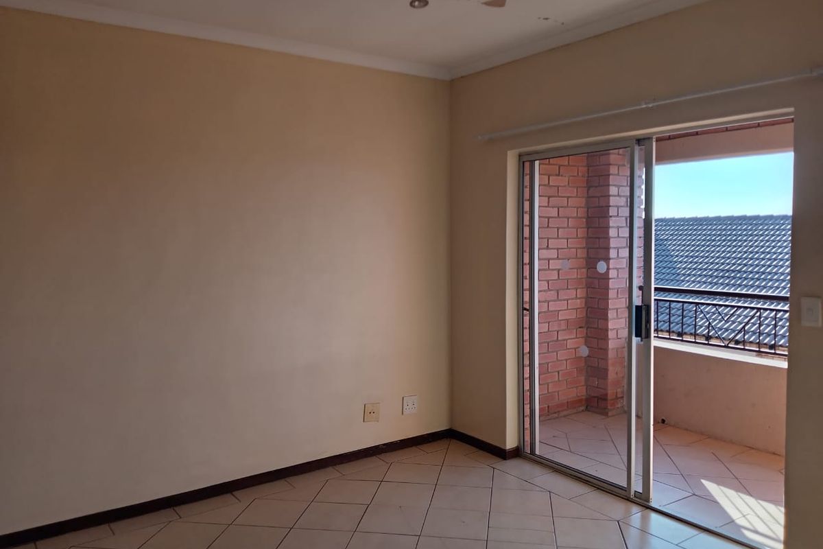 An empty bedroom featuring tiled flooring and a sliding glass door providing access to a private balcony.
