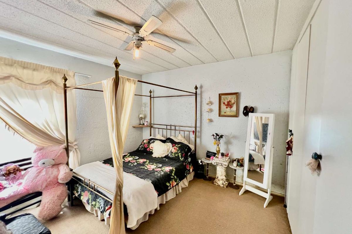 A bedroom featuring a ceiling fan, built-in closet storage, and carpeted flooring, offering a functional space with potential for modernization.