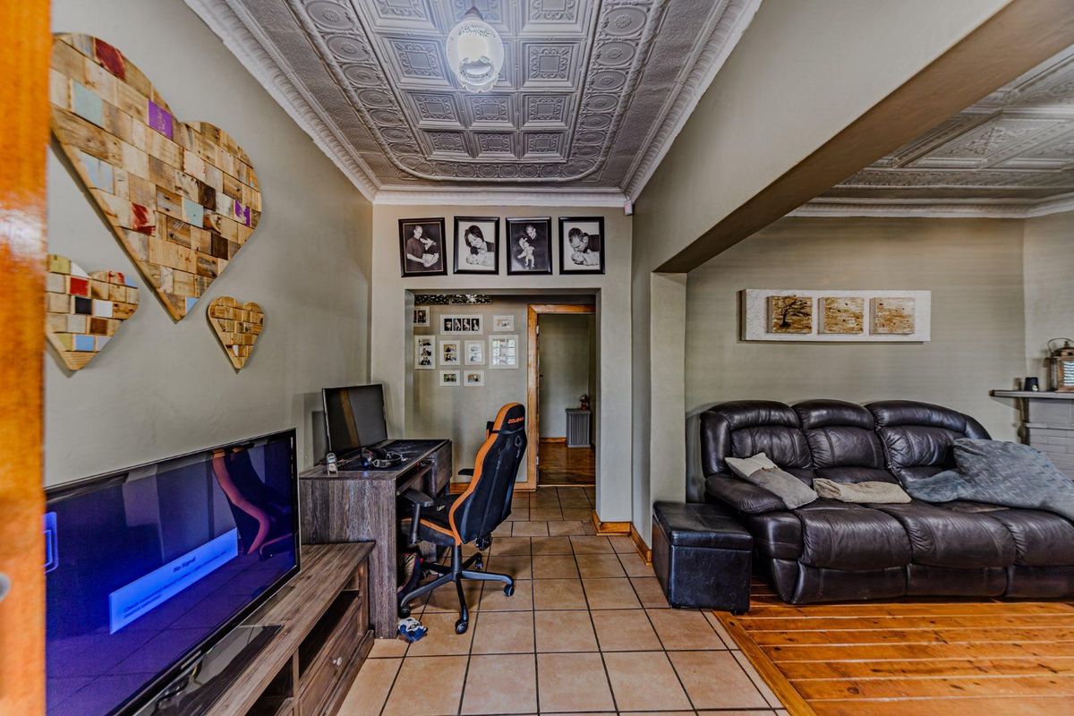 Living area featuring a decorative pressed metal ceiling, a combination of ceramic tiled and timber flooring, and an open-plan layout.