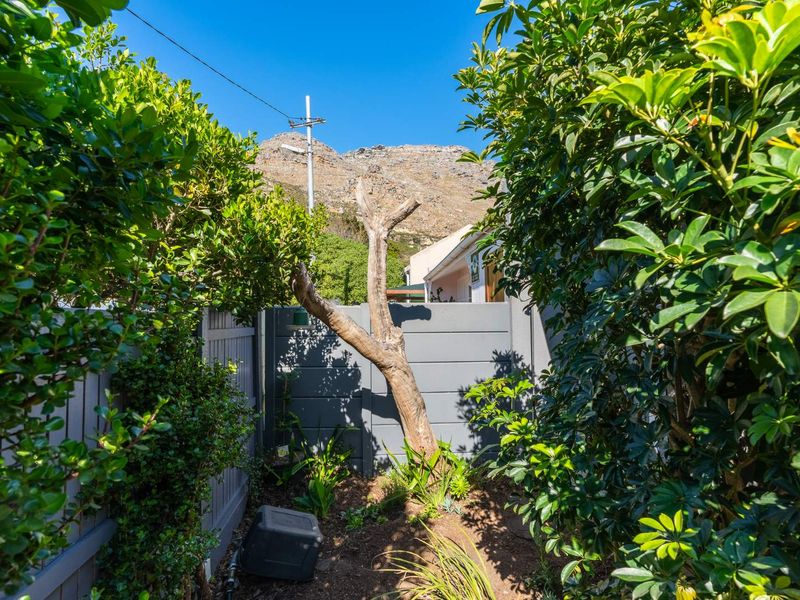 A private garden area featuring established greenery, a boundary wall, and mountain views in the background.
