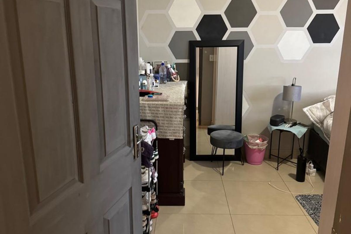A bedroom featuring large format floor tiles and a decorative geometric painted feature wall.