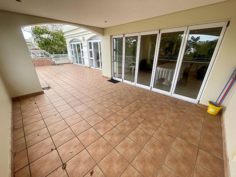 Spacious covered patio featuring tiled flooring and large bi-fold glass doors providing seamless access to the interior living area.