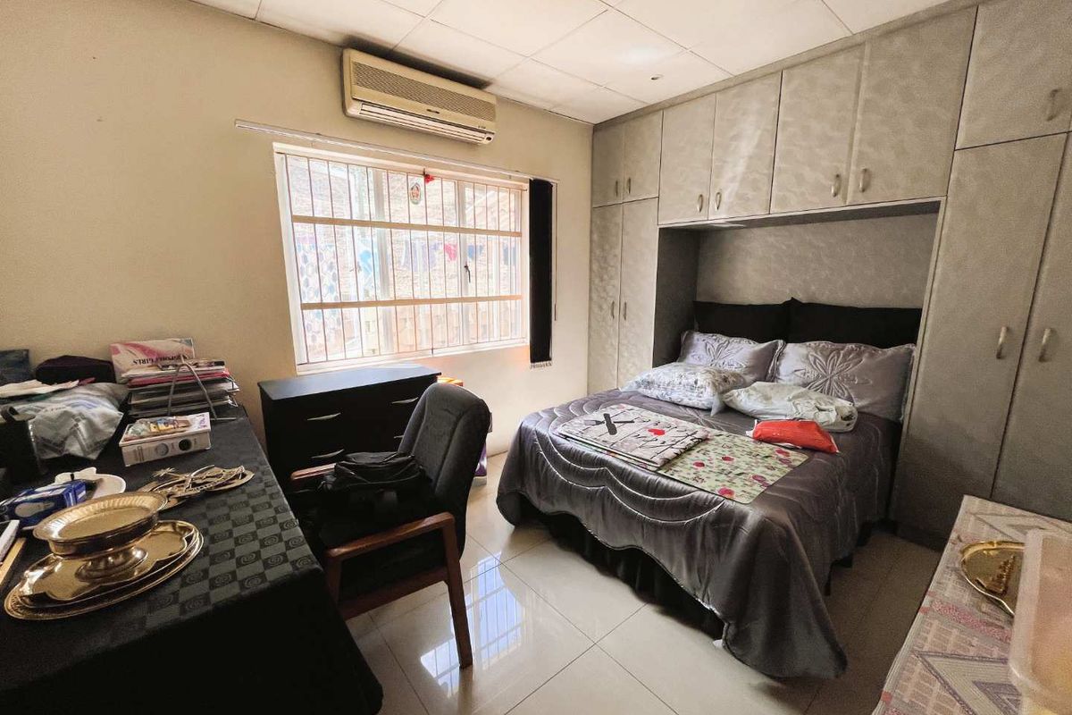 A functional bedroom featuring built-in floor-to-ceiling cabinetry, tiled flooring, and a wall-mounted air conditioning unit.