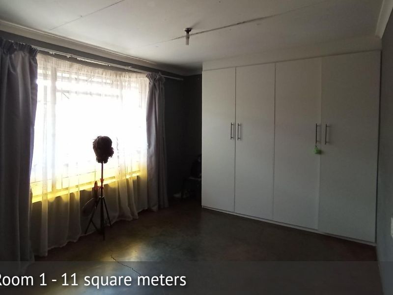 A bedroom featuring built-in cupboards and concrete flooring, offering a functional space ready for personalization.