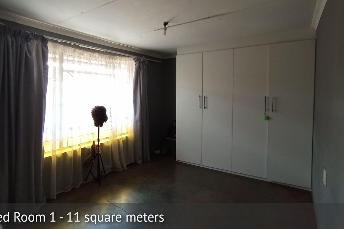 A bedroom featuring built-in cupboards and concrete flooring, offering a functional space ready for personalization.