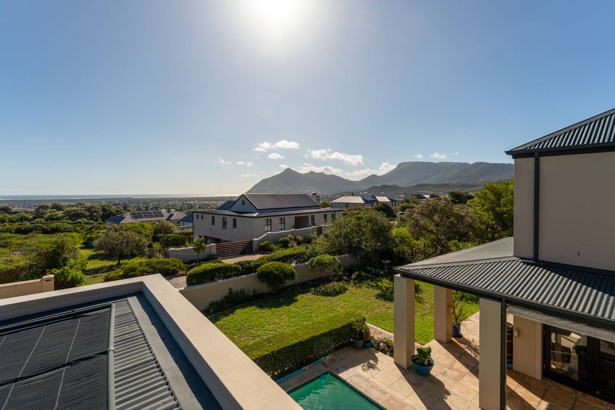 Elevated aerial view of the property featuring a landscaped garden, swimming pool, covered patio, and scenic mountain and coastal views.