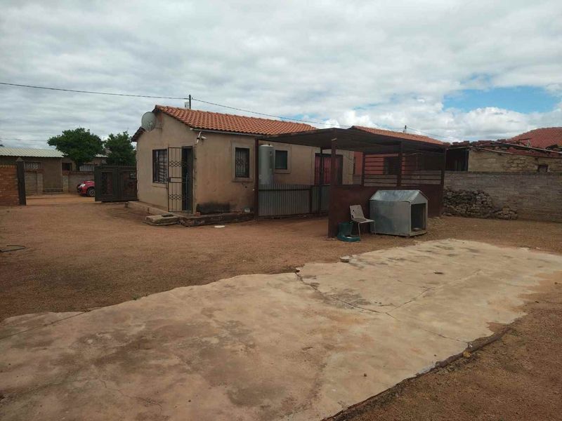 Rear view of the property featuring a covered patio area, concrete slab, and perimeter boundary walling.