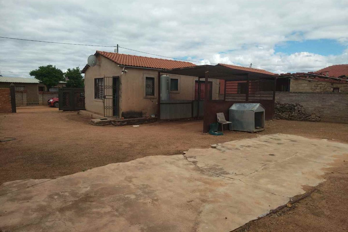 Rear view of the property featuring a covered patio area, concrete slab, and perimeter boundary walling.