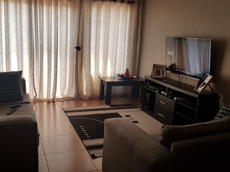 A living room featuring tiled flooring and a large sliding glass door that allows natural light into the space.