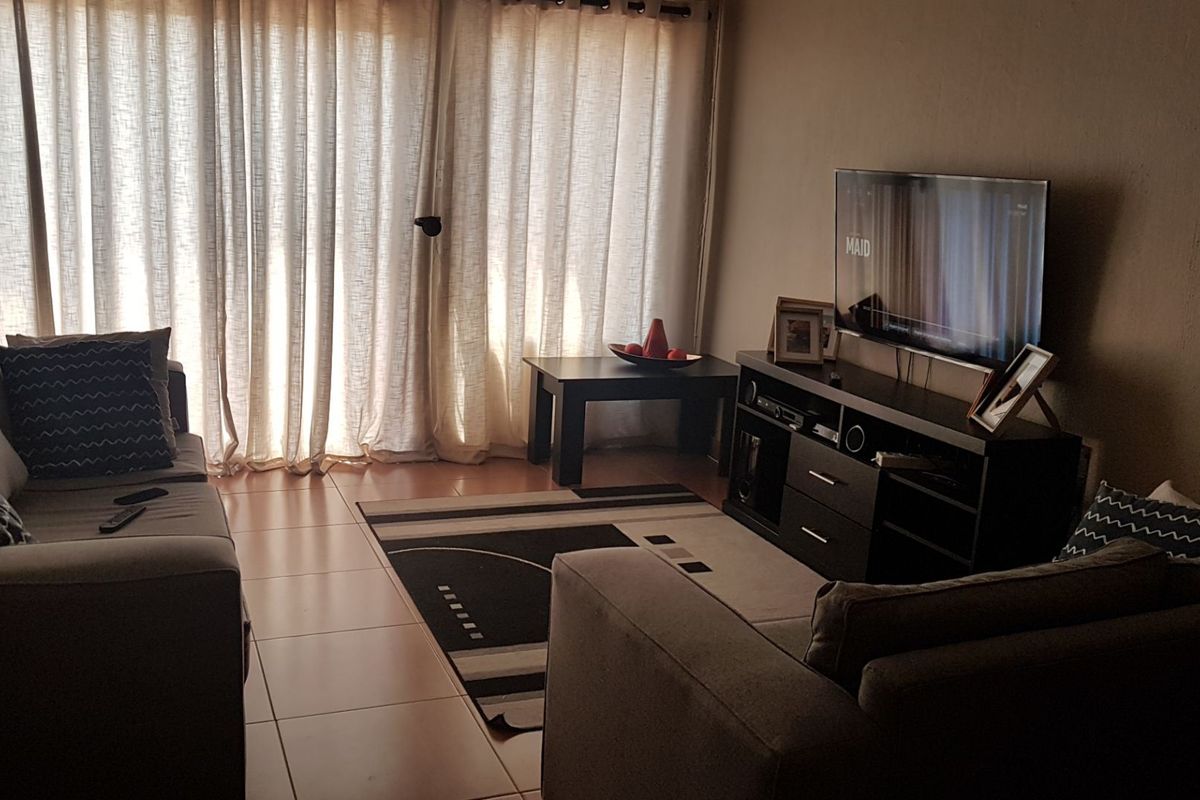 A living room featuring tiled flooring and a large sliding glass door that allows natural light into the space.