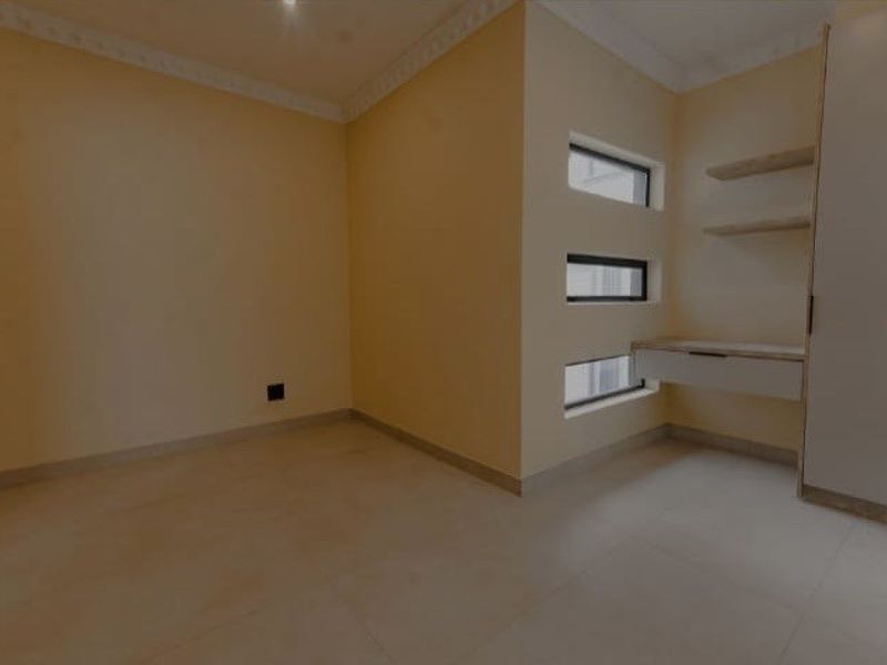 A bright, empty bedroom featuring built-in cabinetry, a floating desk, and modern tiled flooring, offering a clean canvas for personalization.