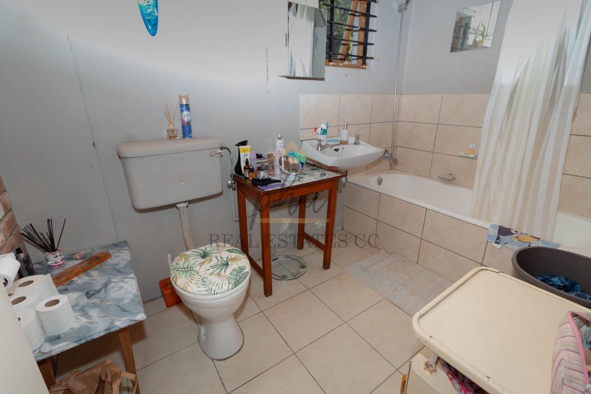 A functional bathroom featuring a standard bathtub, wall-mounted basin, and toilet, with tiled splashbacks and neutral flooring.