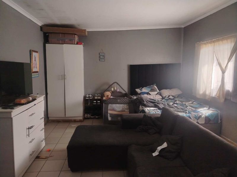 A bedroom featuring tiled flooring and coved ceilings, showing signs of ceiling water staining that may require maintenance.