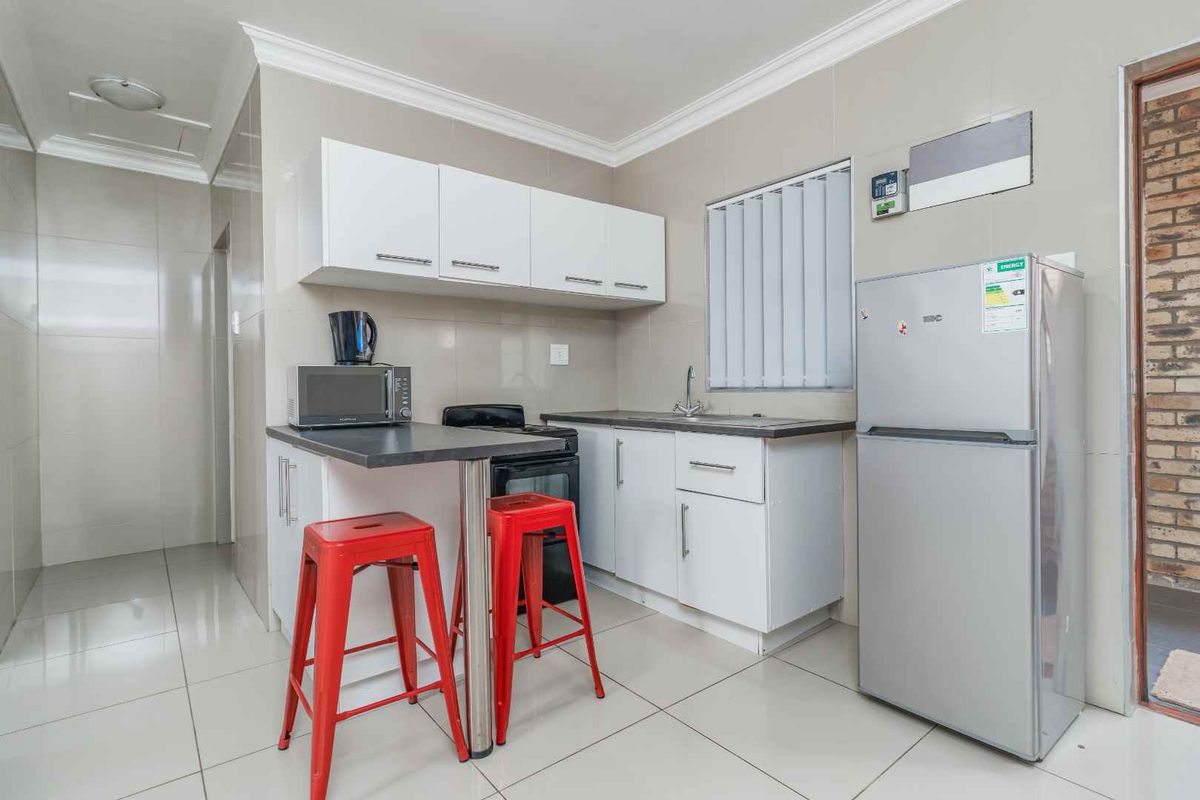 Compact kitchen featuring white cabinetry, tiled flooring, a built-in sink, and a breakfast bar counter.