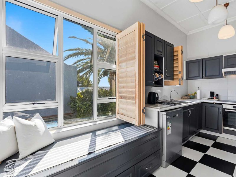 Modern kitchen featuring dark cabinetry, checkerboard flooring, integrated appliances, and a unique built-in window seat with natural light.
