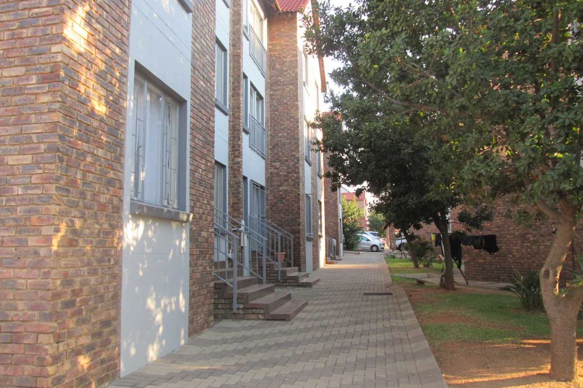 Exterior view of a multi-story apartment complex featuring face brick facades, paved walkways, and established garden areas.