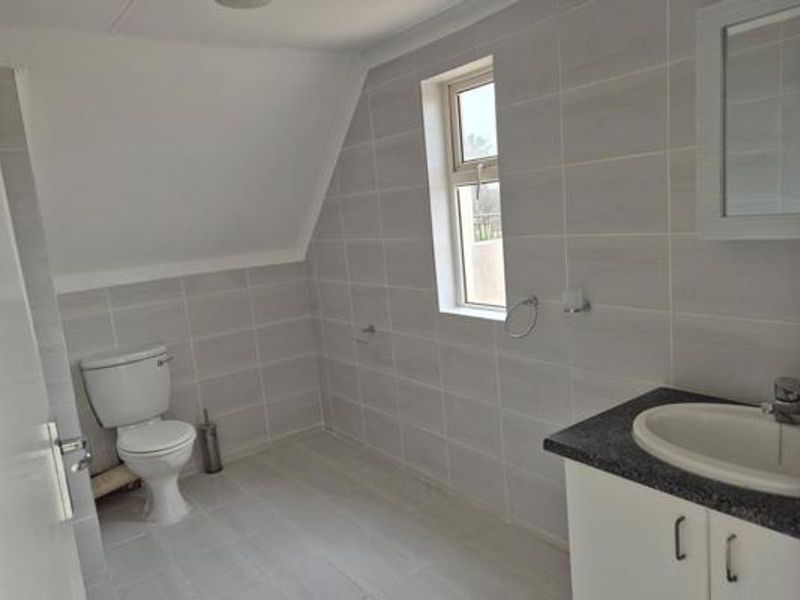 A clean, modern bathroom featuring tiled walls and flooring, a vanity cabinet with a basin, and a built-in mirror cabinet.
