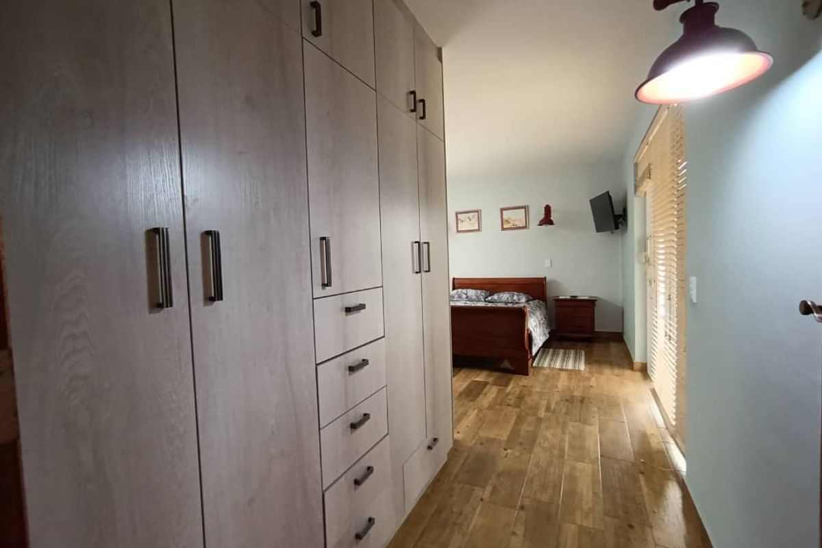 A well-maintained bedroom featuring extensive built-in floor-to-ceiling cabinetry, wood-look flooring, and direct access to an outdoor area through sliding doors.