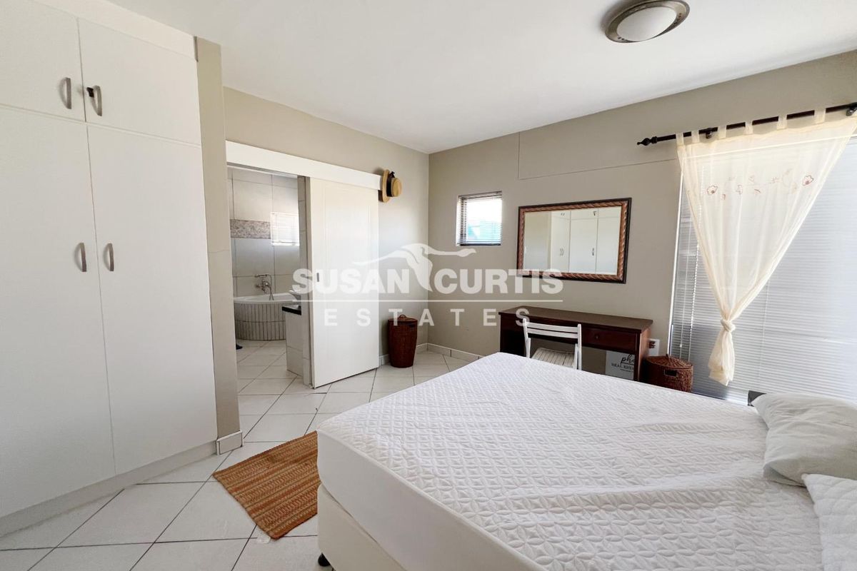 Spacious bedroom featuring built-in cupboards, tiled flooring, and an en-suite bathroom with a sliding door entry.