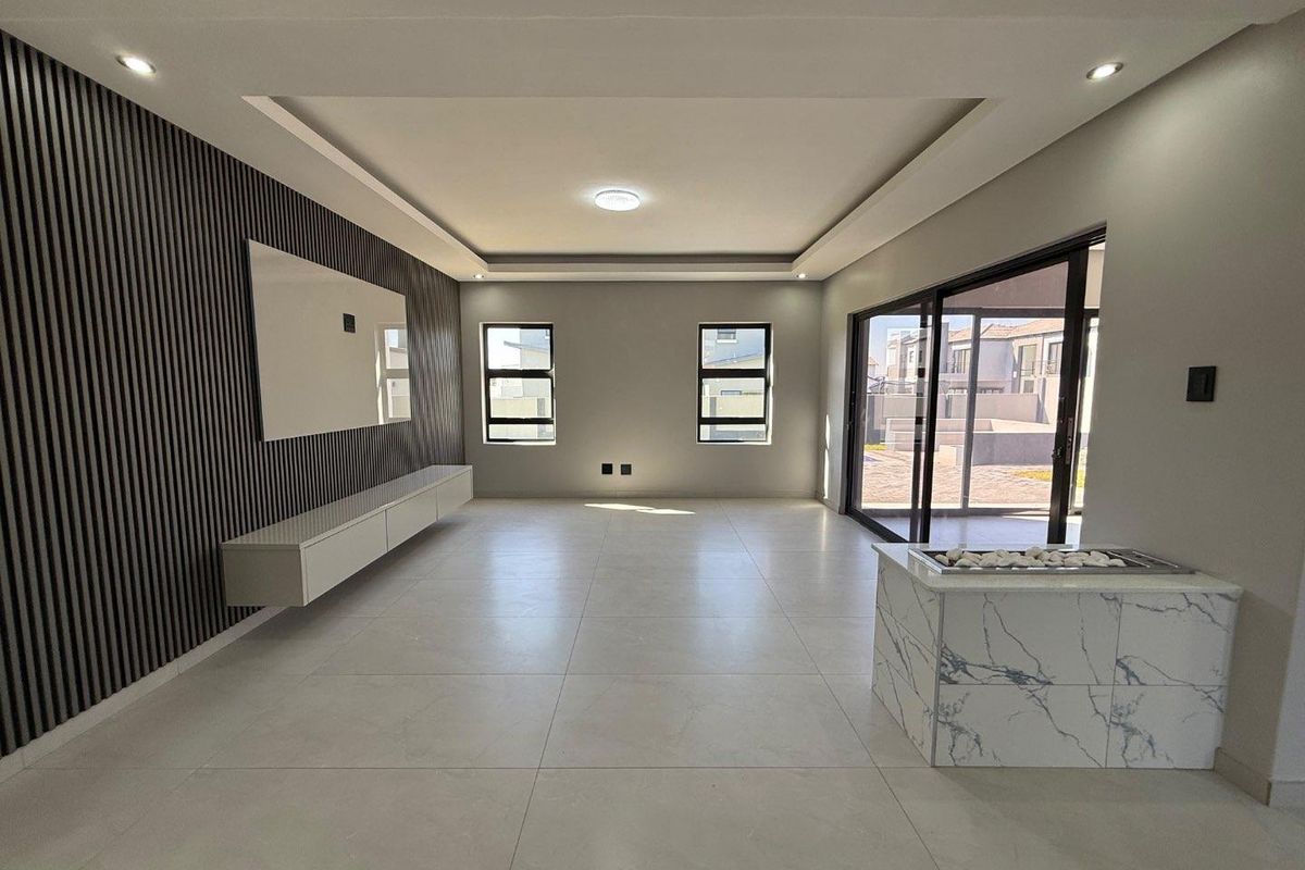 Spacious living area featuring modern tiled flooring, a decorative slatted feature wall with built-in cabinetry, recessed ceiling lighting, and large sliding doors to the exterior.