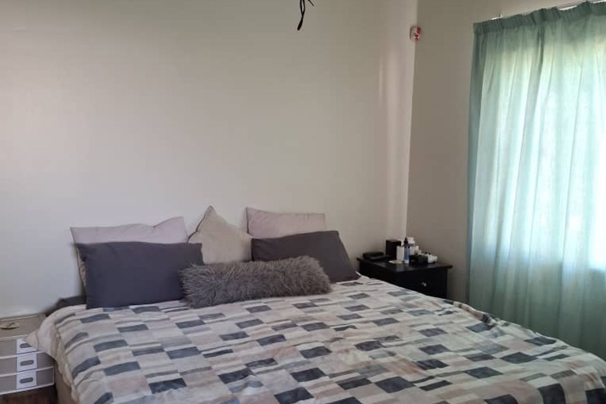 A bedroom featuring neutral walls, tiled flooring, and a ceiling fan with exposed wiring.