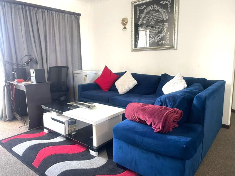 A living room area featuring carpet flooring and window curtain tracks, providing a functional space for relaxation.