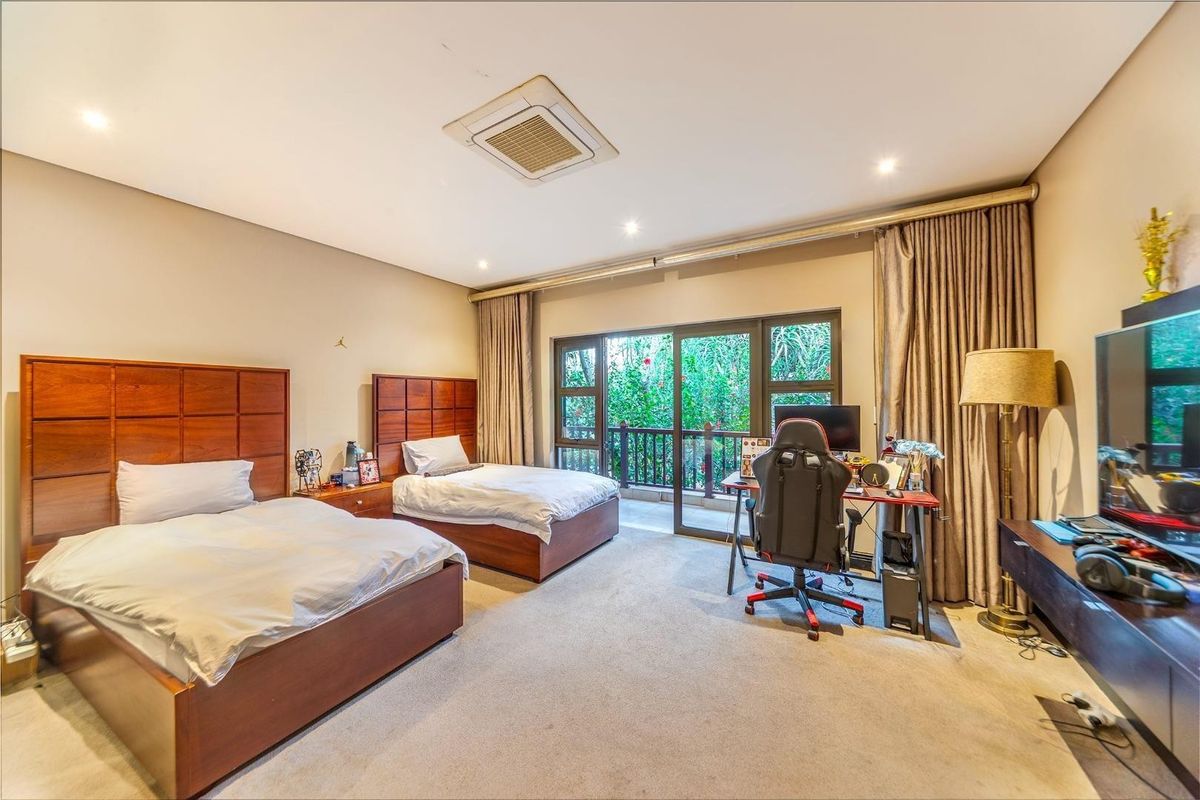 Spacious bedroom featuring neutral carpeting, recessed ceiling lighting, a central air conditioning unit, and large sliding glass doors opening to a private balcony.