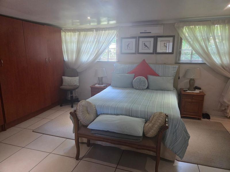 A functional bedroom featuring tiled flooring, a built-in wardrobe, and a wall-mounted split-system air conditioner for climate control.