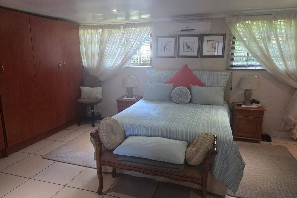 A functional bedroom featuring tiled flooring, a built-in wardrobe, and a wall-mounted split-system air conditioner for climate control.