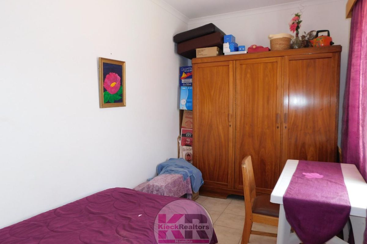 A standard bedroom featuring tiled flooring and coved ceiling details, providing a functional space for rest.