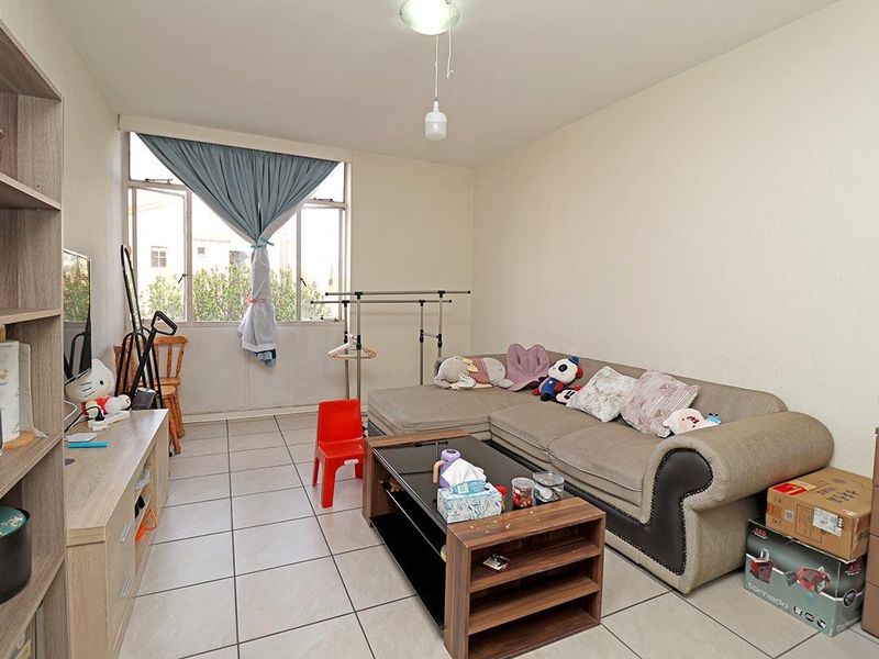 A living room featuring tiled flooring and a large window, providing a functional space ready for personalization.