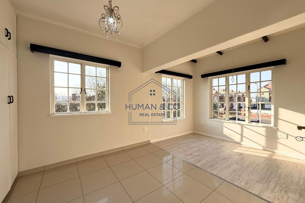 Bright and spacious living area featuring large windows, tiled flooring, and built-in storage cupboards, offering a clean and versatile layout.
