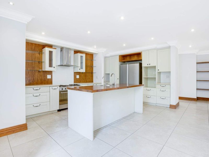 Spacious modern kitchen featuring a central island, ample built-in cabinetry, stainless steel appliances, and neutral tiled flooring with recessed lighting.