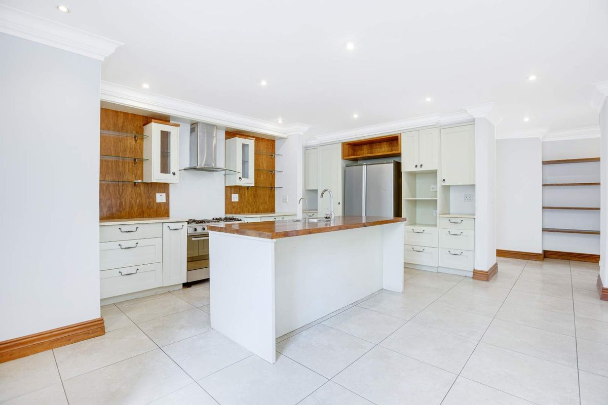 Spacious modern kitchen featuring a central island, ample built-in cabinetry, stainless steel appliances, and neutral tiled flooring with recessed lighting.