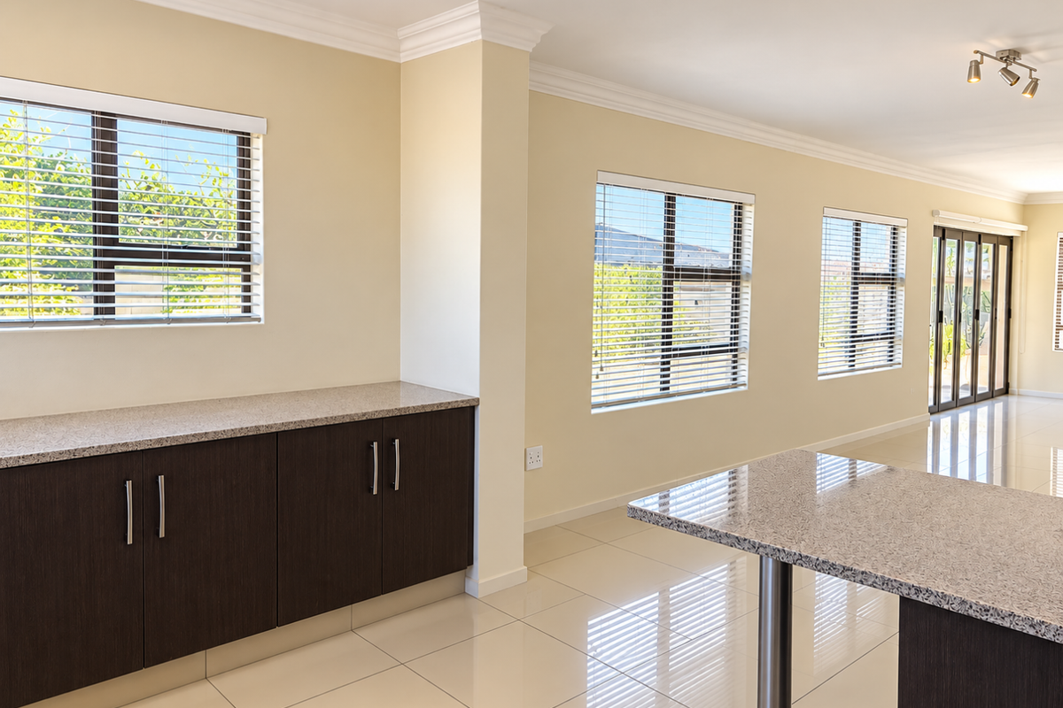Modern kitchen area featuring dark wood cabinetry, granite countertops, polished tile flooring, and large windows with venetian blinds, offering a bright and open layout.