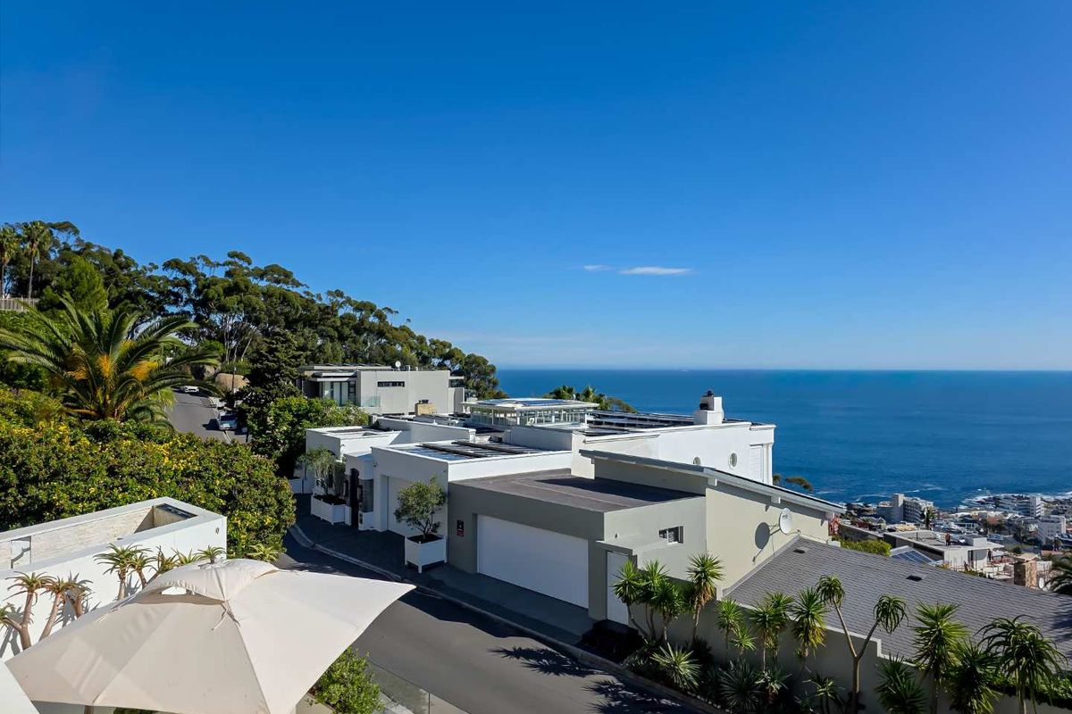 Elevated aerial view of a modern coastal residential property featuring flat roofs, integrated solar panels, and a scenic ocean backdrop.