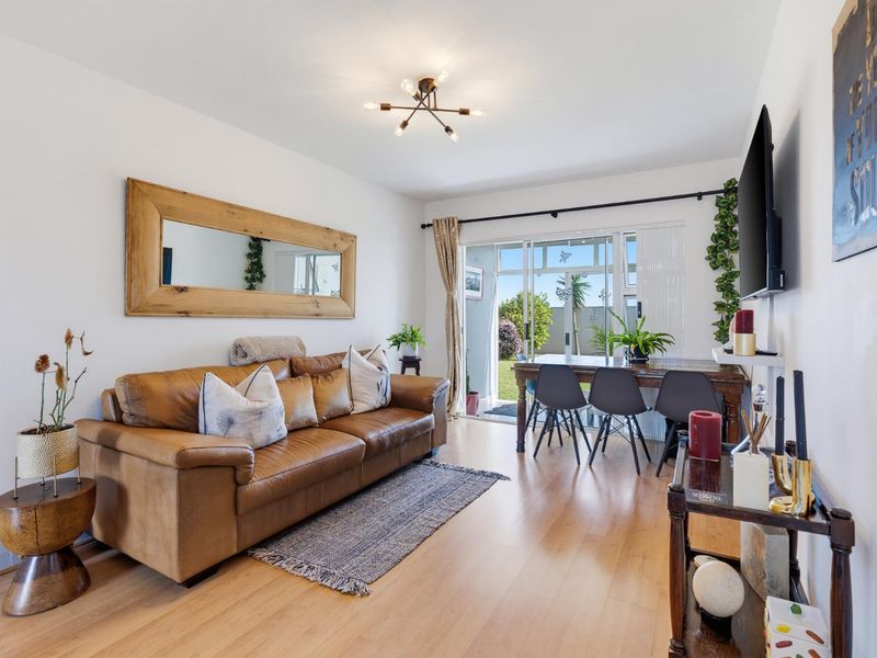 Bright living room featuring laminate flooring and large sliding glass doors that provide direct access to the outdoor area.