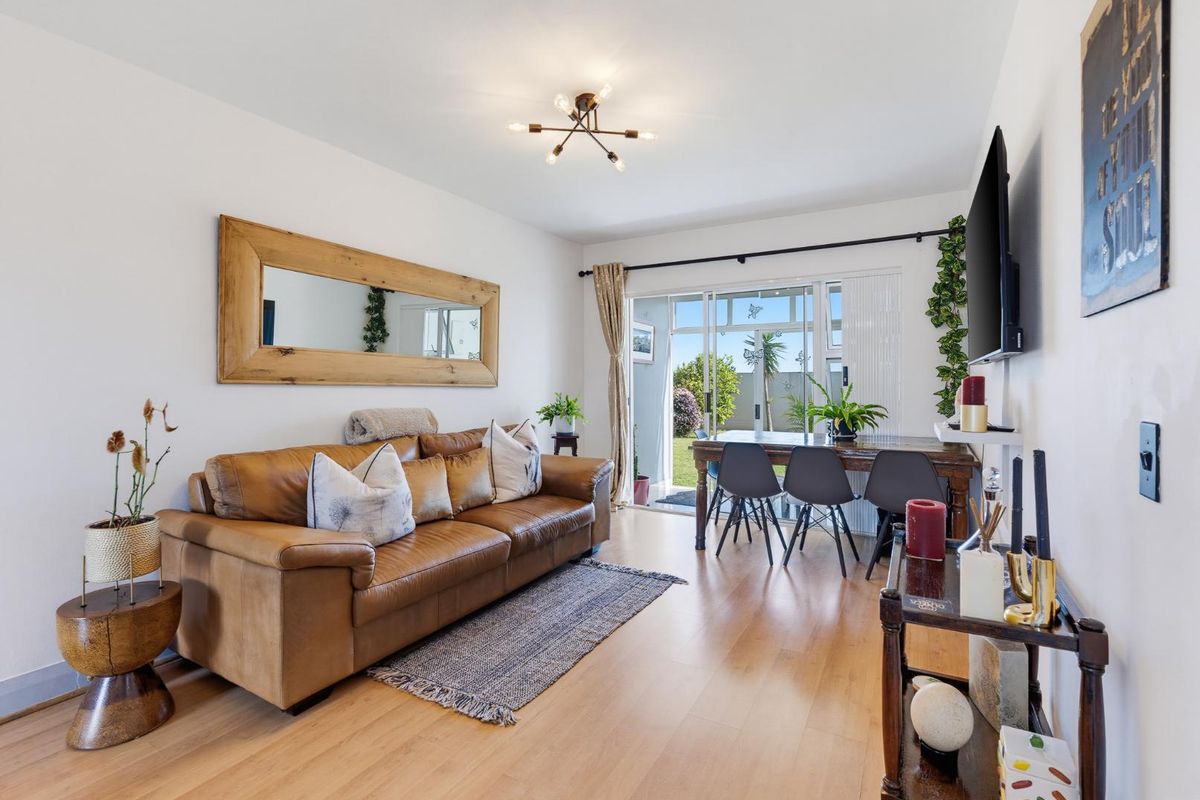 Bright living room featuring laminate flooring and large sliding glass doors that provide direct access to the outdoor area.