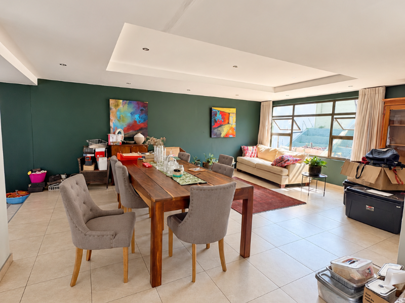 Spacious open-plan living and dining area featuring large windows, tiled flooring, and a recessed ceiling design with integrated lighting.