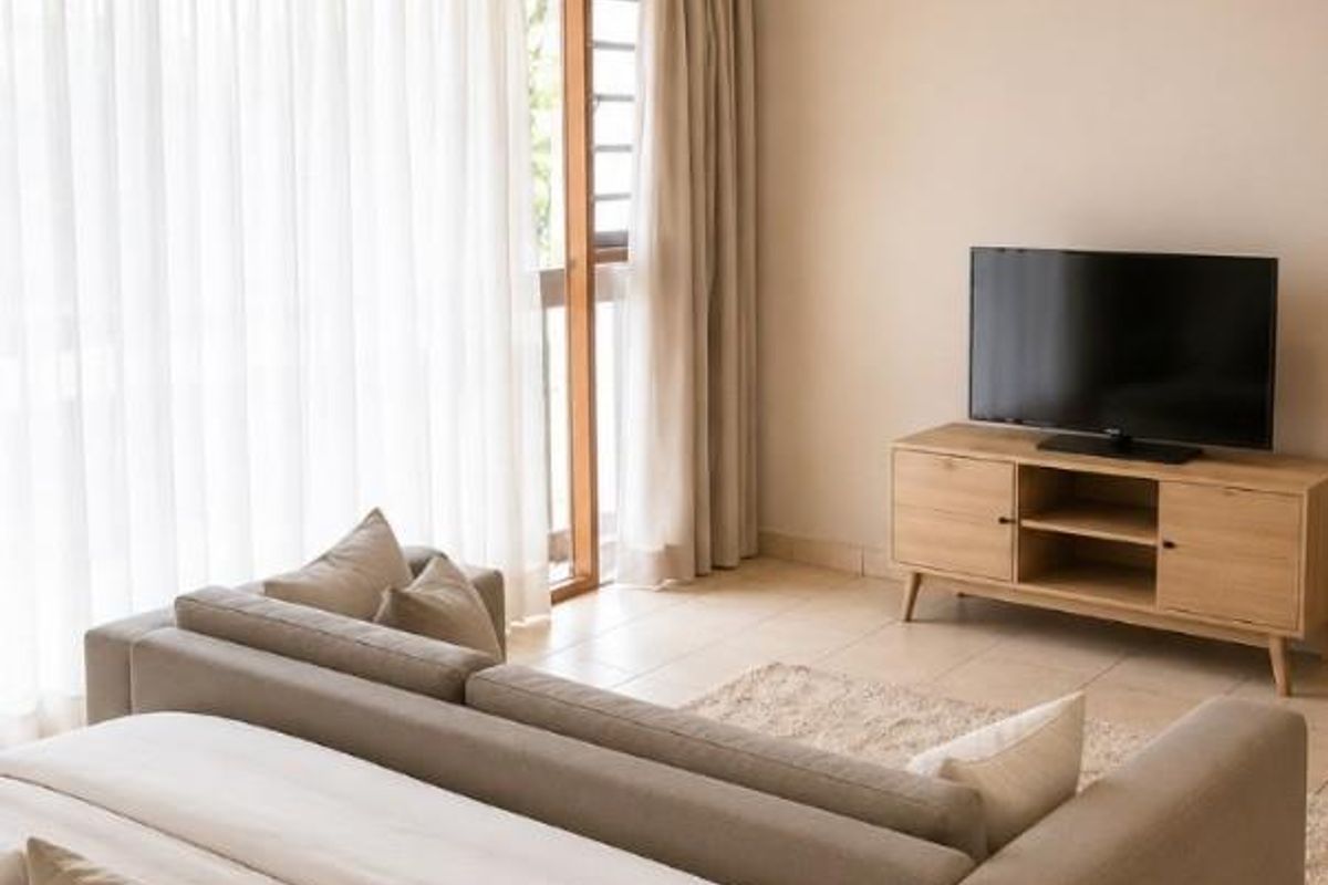 A well-lit bedroom featuring neutral wall tones, tiled flooring, and a large sliding glass door providing access to the exterior.