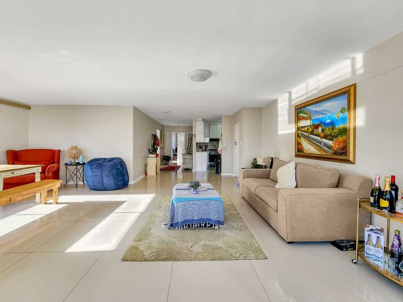 Spacious open-plan living area featuring neutral tiled flooring and a bright, airy layout connecting to the kitchen area.