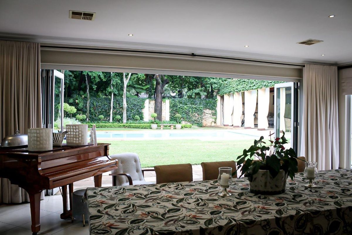 Spacious living area featuring large bi-fold doors that open onto a landscaped garden and swimming pool, creating a seamless indoor-outdoor flow.