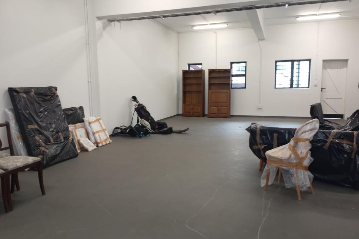 A spacious, open-plan industrial utility area featuring concrete flooring, exposed electrical conduits, and functional windows with security bars.