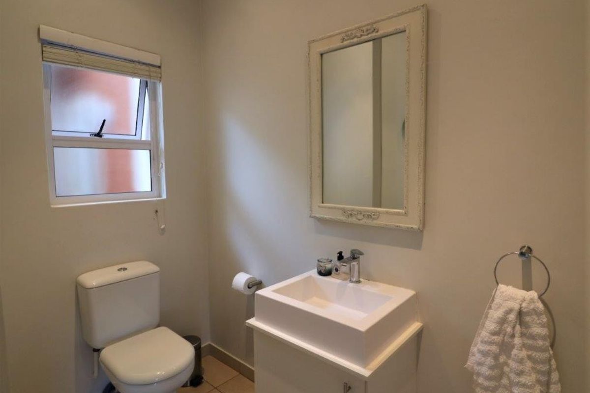 A clean and functional bathroom featuring a modern vanity basin, wall-mounted mirror, and a standard toilet.
