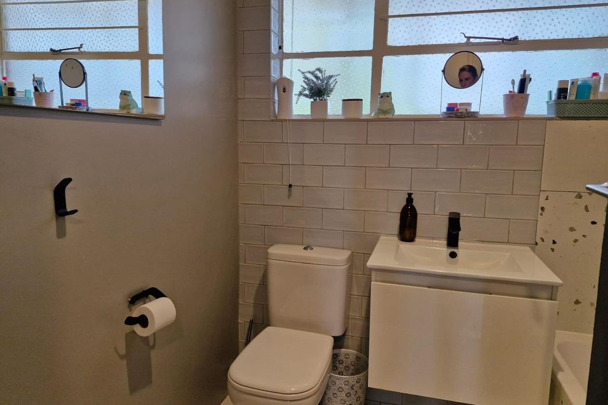 A functional bathroom featuring a wall-mounted vanity with a modern basin, a white toilet, and subway tile splashbacks.