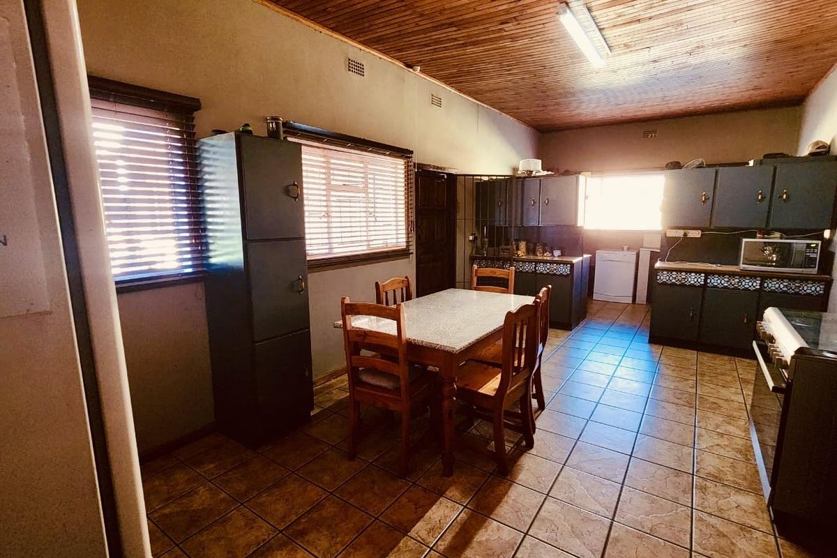 A rustic kitchen featuring dark cabinetry, tiled flooring, and a timber-paneled ceiling, offering a functional layout with integrated cooking appliances.
