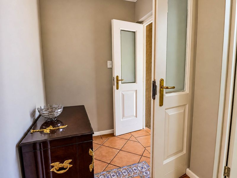 A bright hallway featuring tiled flooring and classic white doors with frosted glass panels and brass hardware.