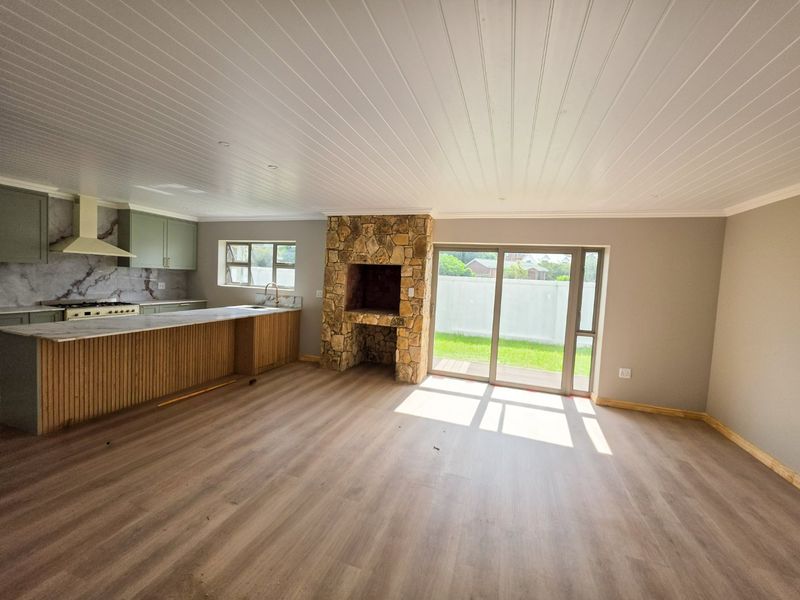 Spacious open-plan living area featuring a stone fireplace, modern kitchen with island, and sliding doors leading to the garden.